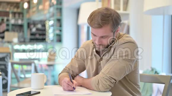 严肃的年轻人在咖啡厅做文书工作视频的预览图