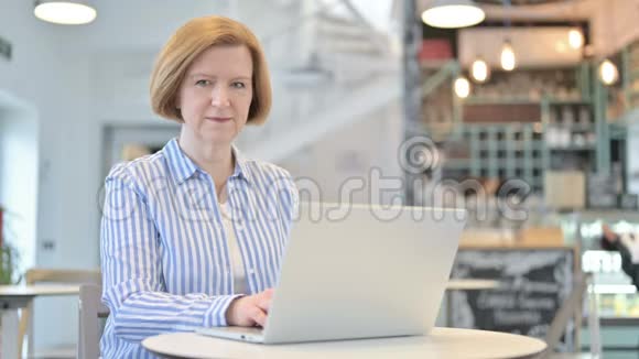 创意老女人在咖啡厅用笔记本电脑竖起大拇指视频的预览图