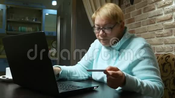 老年妇女在线购买使用笔记本电脑和塑料卡视频的预览图