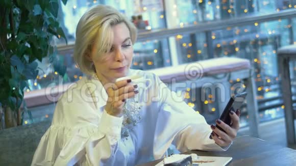 优雅时尚的金发女人坐在咖啡馆里用手机视频的预览图