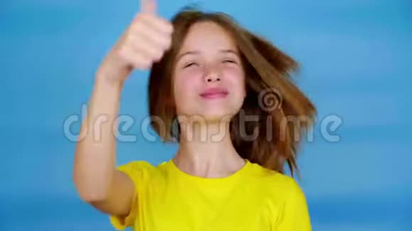 穿着黄色t恤的快乐少女微笑着竖起大拇指喜欢并看着镜头视频的预览图