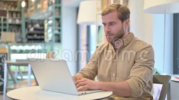 青年男子因在咖啡厅的笔记本电脑上丢失而心烦意乱视频的预览图