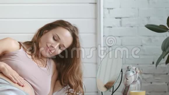 特写孕妇在家床上微笑美丽的妈妈在说肚子视频的预览图