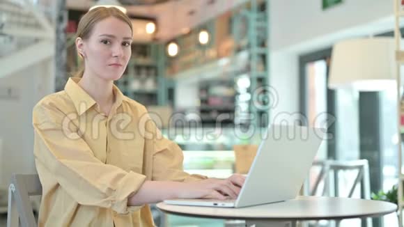 不是咖啡馆里拿着笔记本电脑的年轻女子做的手势视频的预览图