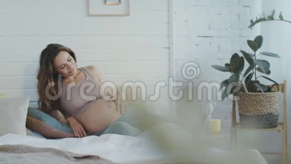 孕妇在床上感觉宝宝在肚子里踢令人惊讶的肚皮妈妈视频的预览图