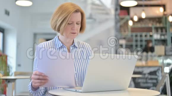 创意老女人在咖啡厅手提电脑及文件视频的预览图