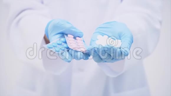 医生穿着医疗服手里拿着许多白色的小药丸和两包蓝色和粉红色的水泡视频的预览图