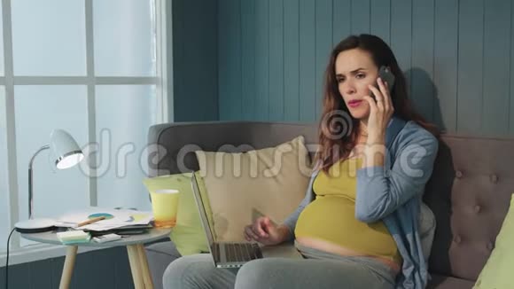 怀孕女商人在沙发上讲手机带笔记本电脑的肚皮妈妈视频的预览图
