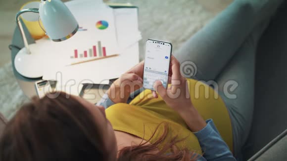 怀孕的女商人在家里的智能手机上缓慢地发短信视频的预览图