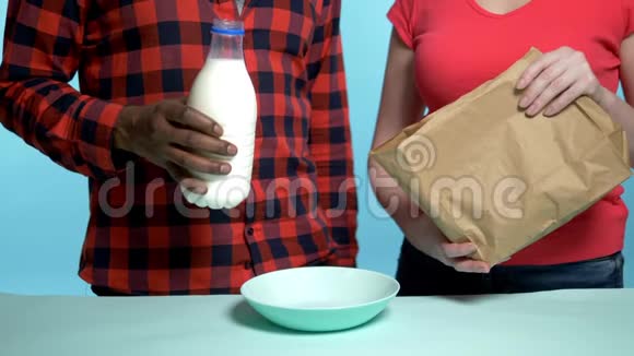 男性非洲高加索女人用牛奶做早餐麦片蓝色背景视频的预览图