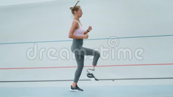 残疾妇女在锻炼时做高膝关节敲击在赛马场慢跑的运动员视频的预览图