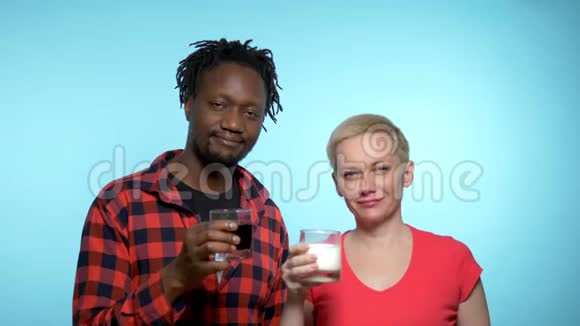 非洲男人和白种人女人喝黑白鸡尾酒蓝色背景视频的预览图