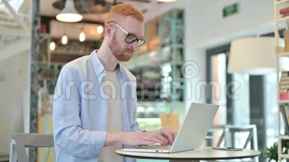 不红发男子用手提电脑做手指手势视频的预览图