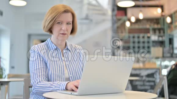 创意老女人与笔记本电脑冲击咖啡厅视频的预览图
