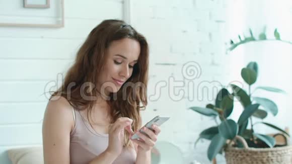 微笑着怀孕的肚子妈妈在卧室里用手机聊天视频的预览图