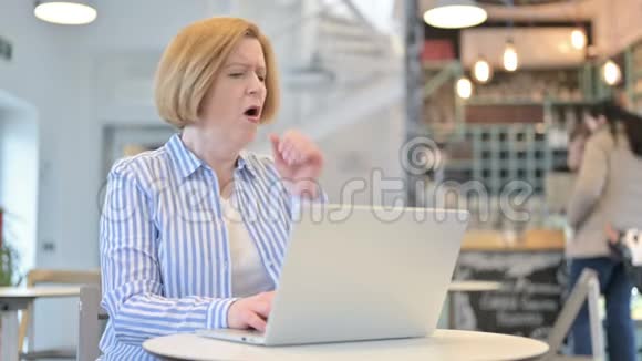 创意老女人在咖啡厅用手提咳嗽视频的预览图
