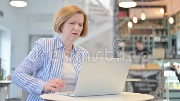 有创意的老女人用笔记本电脑做背痛视频的预览图