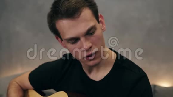 穿着黑色T恤的白人弹吉他用吉他演奏男性的手专业人员视频的预览图