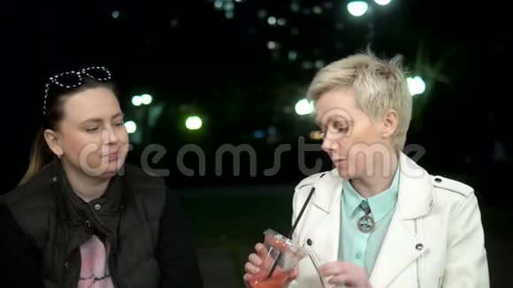 两个女人晚上在街上聊天喝着鸡尾酒视频的预览图