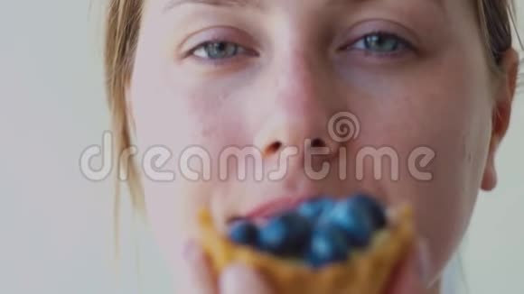 美丽的年轻的女孩吃着一篮子浆果和蓝莓微笑着视频的预览图