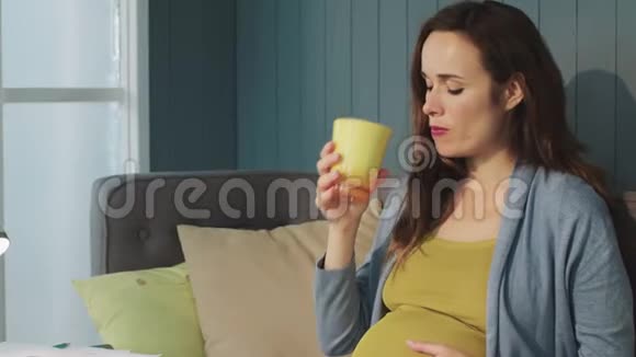 在客厅里用玻璃杯子喝酒的孕妇视频的预览图