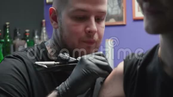 青年纹身师在沙龙纹身蛇的视频视频的预览图