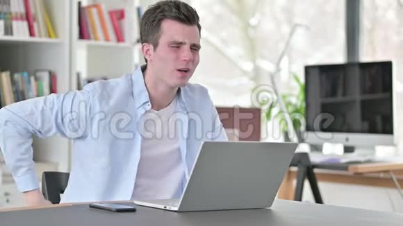 背疼的年轻人在手提电脑视频的预览图