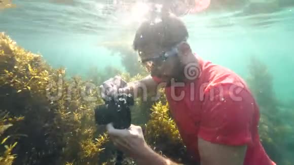 白种人男性持有DSLR相机与三脚架水下视频的预览图