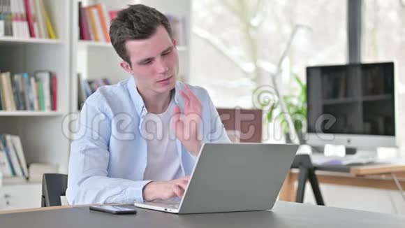 颈部疼痛的年轻人在做手提电脑视频的预览图