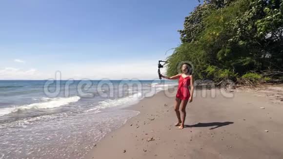 一位女性vlogger在海滩上散步并为vlog录制自拍视频视频的预览图