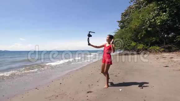 年轻的千禧社交媒体影响者在海滩上散步和拍摄视频视频的预览图
