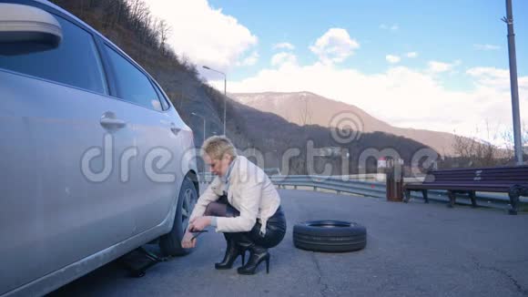 美丽的女孩换了一辆停在路边的汽车的车轮视频的预览图