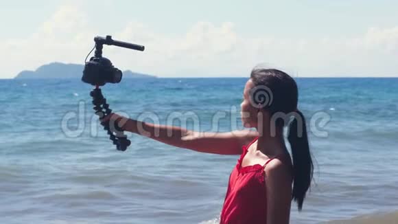 一位年轻的女性vlogger持DSLR相机与三脚架和拍摄的肖像视频的预览图