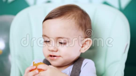 可爱的小男孩坐在椅子上吃橘子或橘子生日帅哥视频的预览图