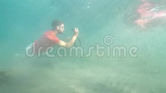 一名男子用数码相机拍摄水下浮潜女子视频的预览图
