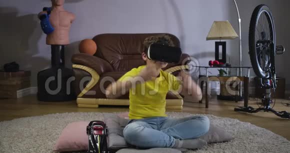年轻的白种人卷发男孩在戴着虚拟现实谷歌和交谈时有感情地做手势黄色T的好学生视频的预览图