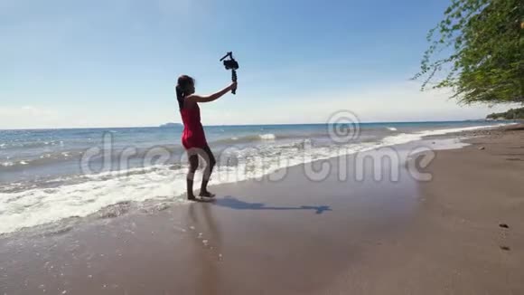 旅行妇女vlogger在海滩上散步并在DSLR相机上记录vlog视频的预览图