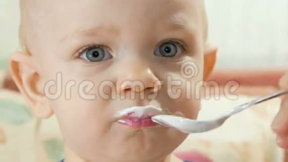 有魅力的宝宝用妈妈的勺子吃奶酪孩子一年特写视频的预览图