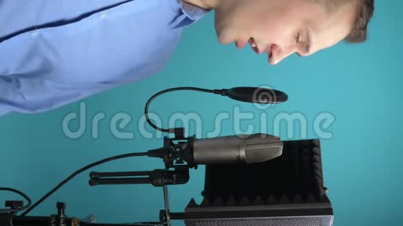 垂直图像在录音室对着麦克风唱歌的男人视频的预览图