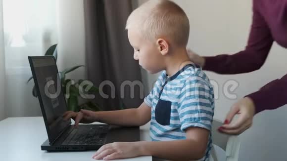 在家里和妈妈一起在电脑上工作的男孩电子课程儿童教育视频的预览图