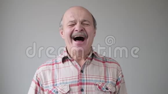 年长的秃头西班牙裔男子无聊打哈欠视频的预览图
