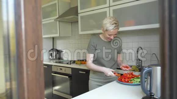 女人在家里的厨房里切蔬菜做零食视频的预览图