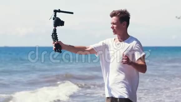 年轻男性vlogger在海滩上拍摄旅行故事视频的预览图