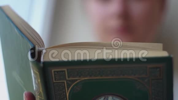 书脊的特写厚厚的一本艺术书的封面在背景中读到一个女孩视频的预览图