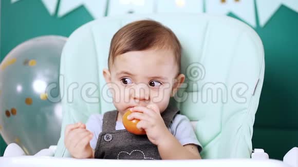 可爱的小男孩坐在椅子上吃橘子或橘子生日帅哥视频的预览图