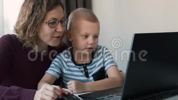 在家里和妈妈一起在电脑上工作的男孩电子课程儿童教育视频的预览图