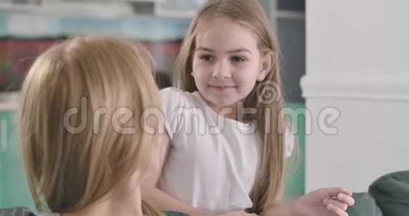 可爱的白种人女孩的特写脸棕色的眼睛抚摸着母亲头发笑着有趣的孩子在表达视频的预览图