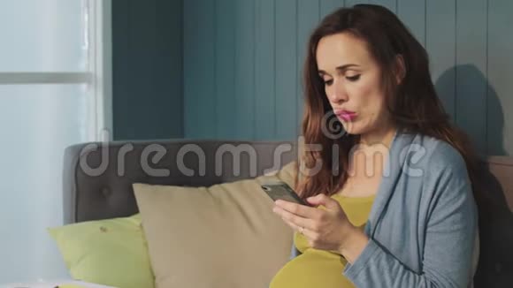 宏观孕妇触摸手机屏幕沙发在家视频的预览图