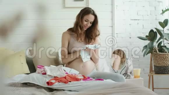 幸福孕妇抱婴儿衣床可爱的妈妈喜欢婴儿用品视频的预览图