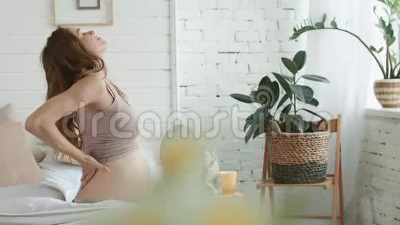孕妇在卧室里伸展身体在家中提供备孕的坐床视频的预览图